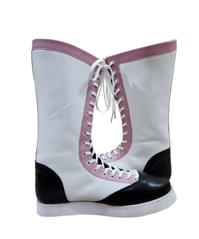 May include: A pair of white wrestling boots with black and pink accents. The boots have laces up the front and a thick white sole.