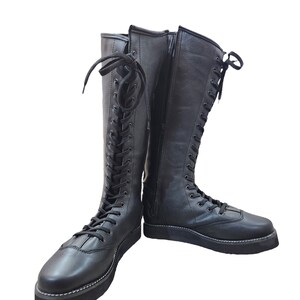 May include: A pair of black leather lace-up boots with a zipper on the side. The boots have a thick platform sole and are tied with black laces.