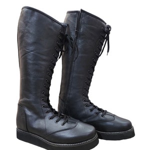 May include: A pair of black leather knee-high boots with lace-up fronts and side zippers. The boots have a thick platform sole.
