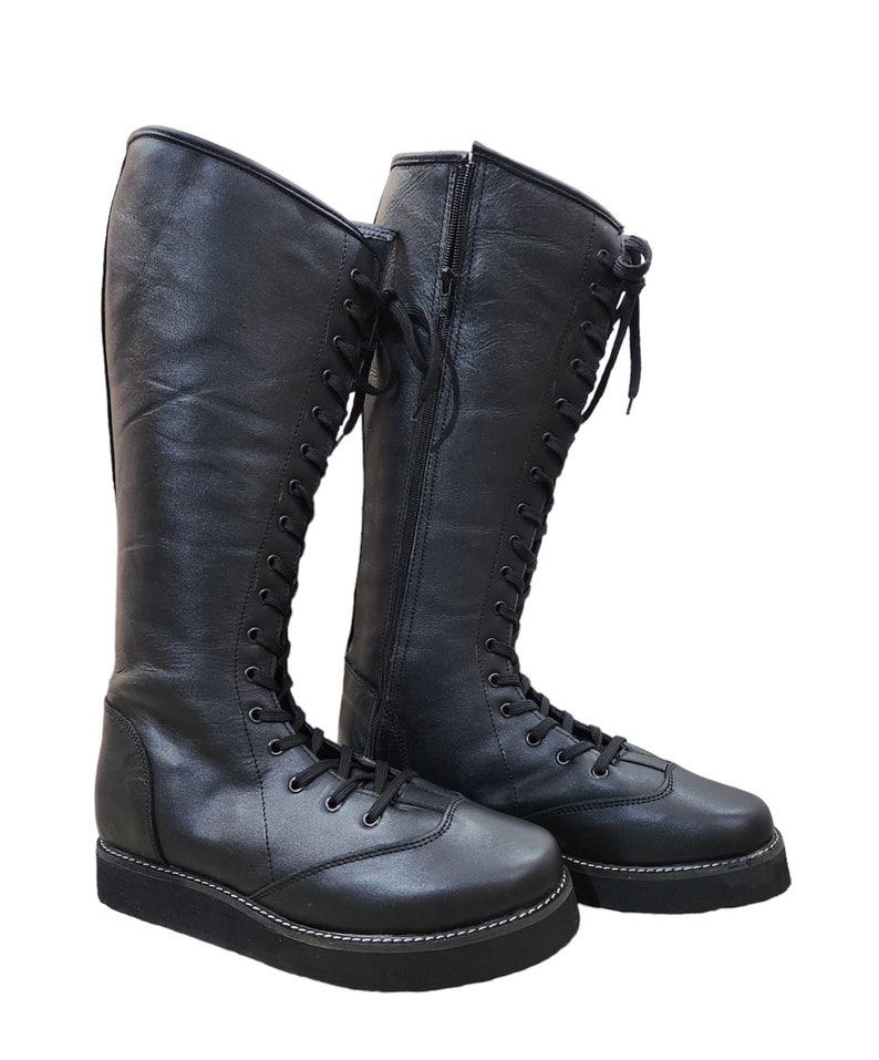 May include: A pair of black leather knee-high boots with lace-up fronts and side zippers. The boots have a thick platform sole.