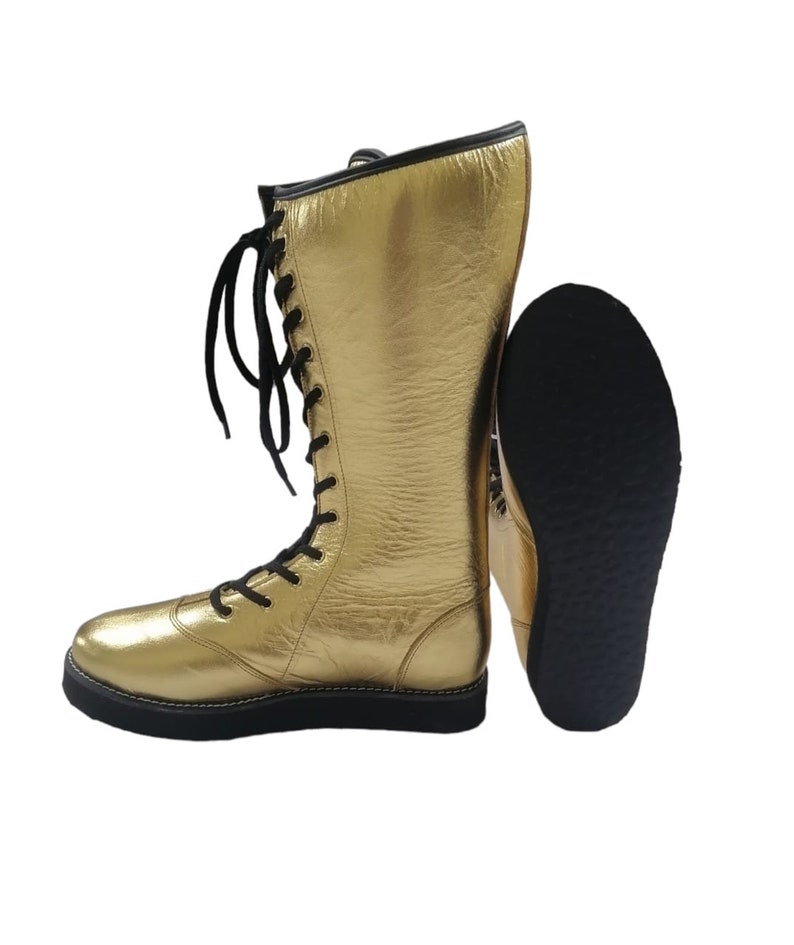 May include: A pair of gold wrestling boots with black laces and a black rubber sole.