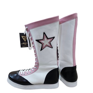 May include: White wrestling boots with black and pink accents. The boots have a star design on the side and are laced up the front. The boots are made by Riccoflex International LTD.