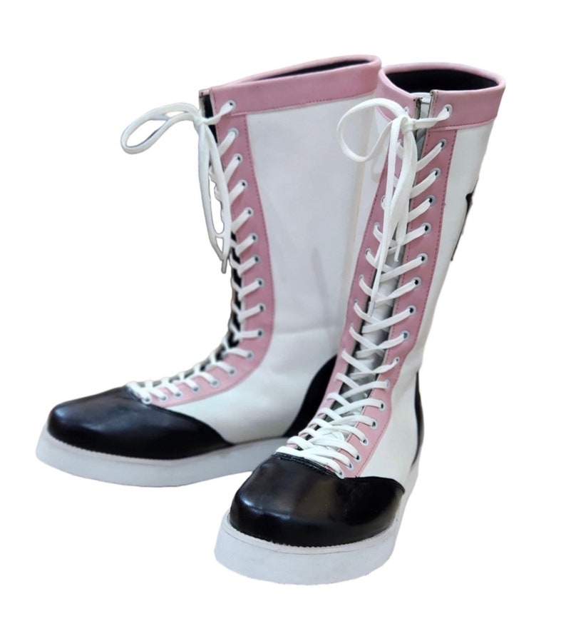 May include: A pair of white and black wrestling boots with pink accents and white laces.