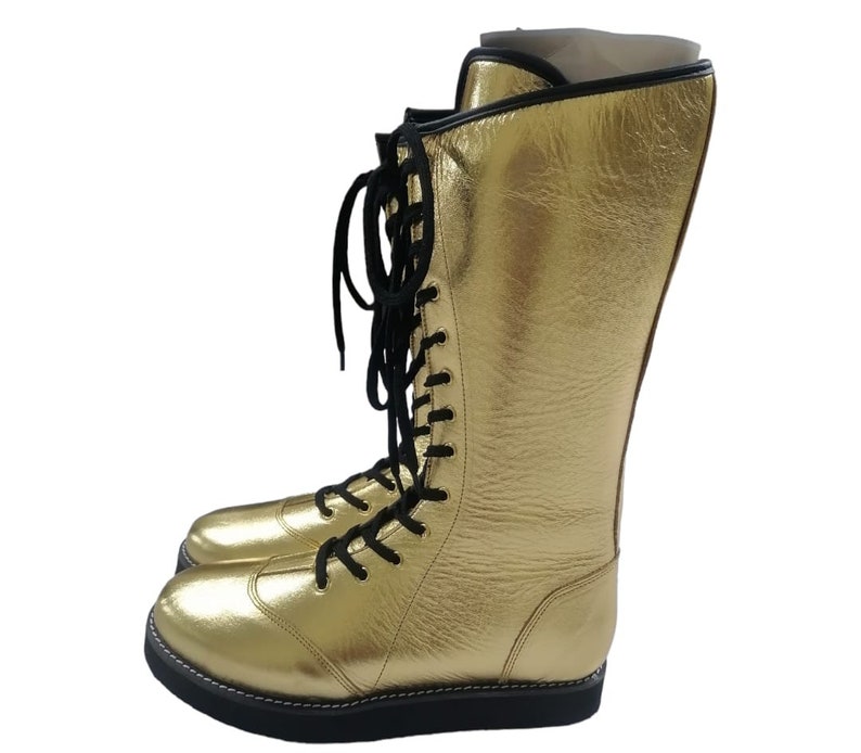 May include: Gold wrestling boots with black laces. The boots are tall and have a thick sole.
