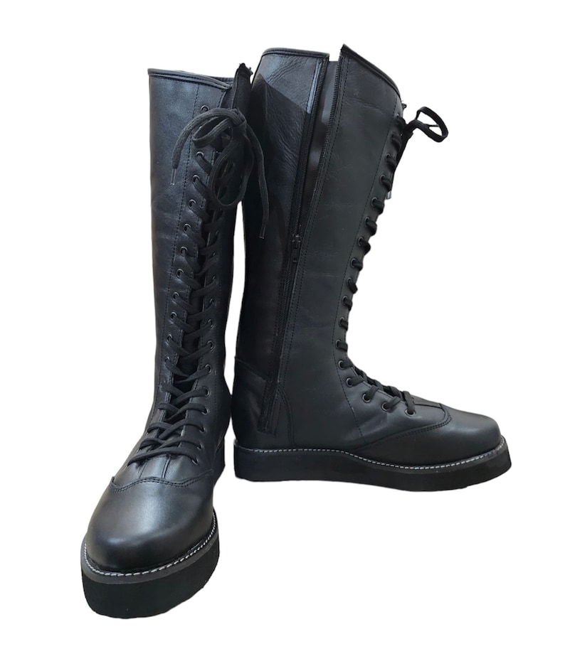 May include: A pair of black leather knee-high boots with lace-up fronts and side zippers. The boots have a thick platform sole.