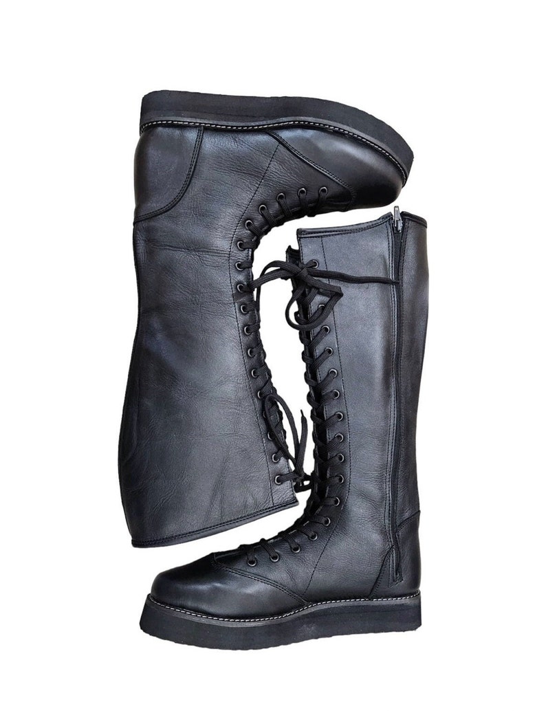 May include: A pair of black leather knee-high boots with laces and a zipper on the side. The boots have a thick platform sole.