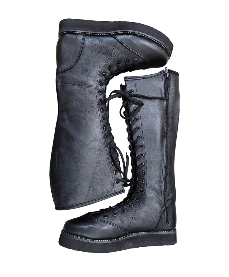 May include: A pair of black leather knee-high boots with laces and a zipper on the side. The boots have a thick platform sole.