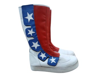 Può includere: Paio di stivali alti dal design patriottico. Gli stivali presentano una base bianca, gambali rossi e pannelli blu ornati di stelle bianche. Gli stivali hanno una suola platform e un design a stelo alto, adatti per cosplay o eventi a tema.