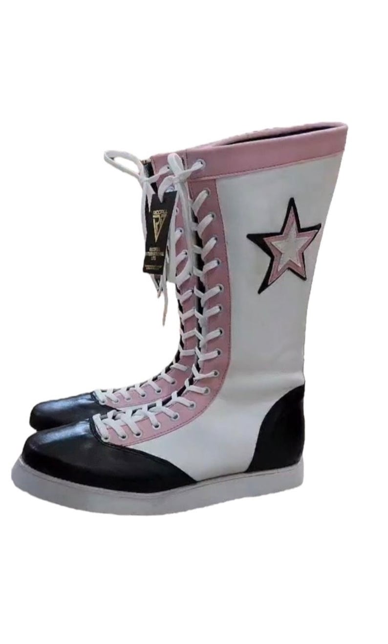 May include: White and black wrestling boots with pink accents and a white star on the side. The boots are laced up and have a white sole.