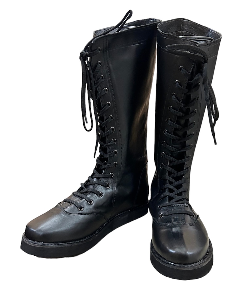 Puede incluir: Un par de botas negras de cuero hasta la rodilla con cordones en la parte delantera y suelas gruesas.