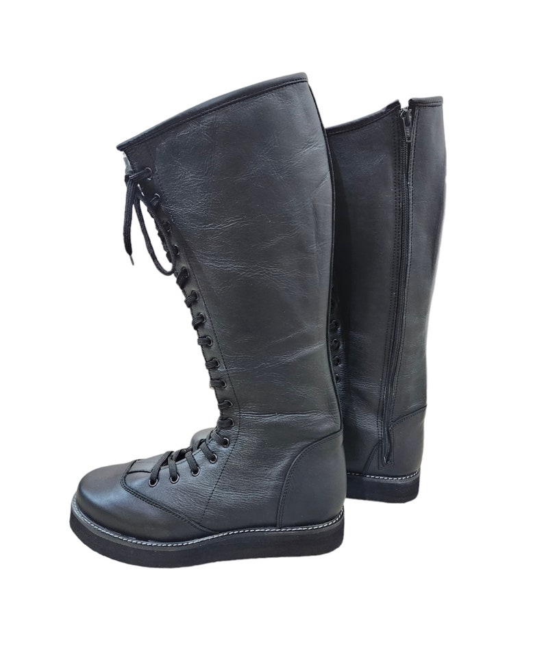 May include: A pair of black leather wrestling boots with laces up the front and a zipper on the back.