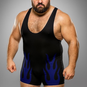 Può includere: Un body da wrestling nero con disegni di fiamme blu sulle gambe. Il body ha uno scollo tondo. La persona che lo indossa ha la barba e un'espressione severa. Lo sfondo è grigio.