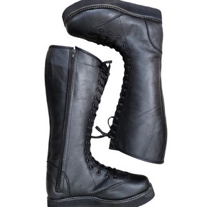 May include: Black leather knee-high boots with a lace-up front and a zipper on the side. The boots have a thick platform sole.