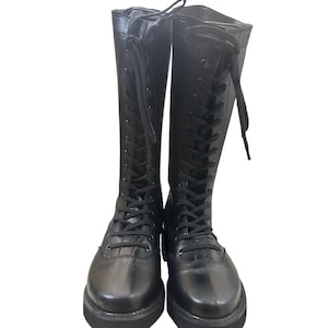 Puede incluir: Botas negras de cuero hasta la rodilla con cordones en la parte delantera y suelas gruesas.
