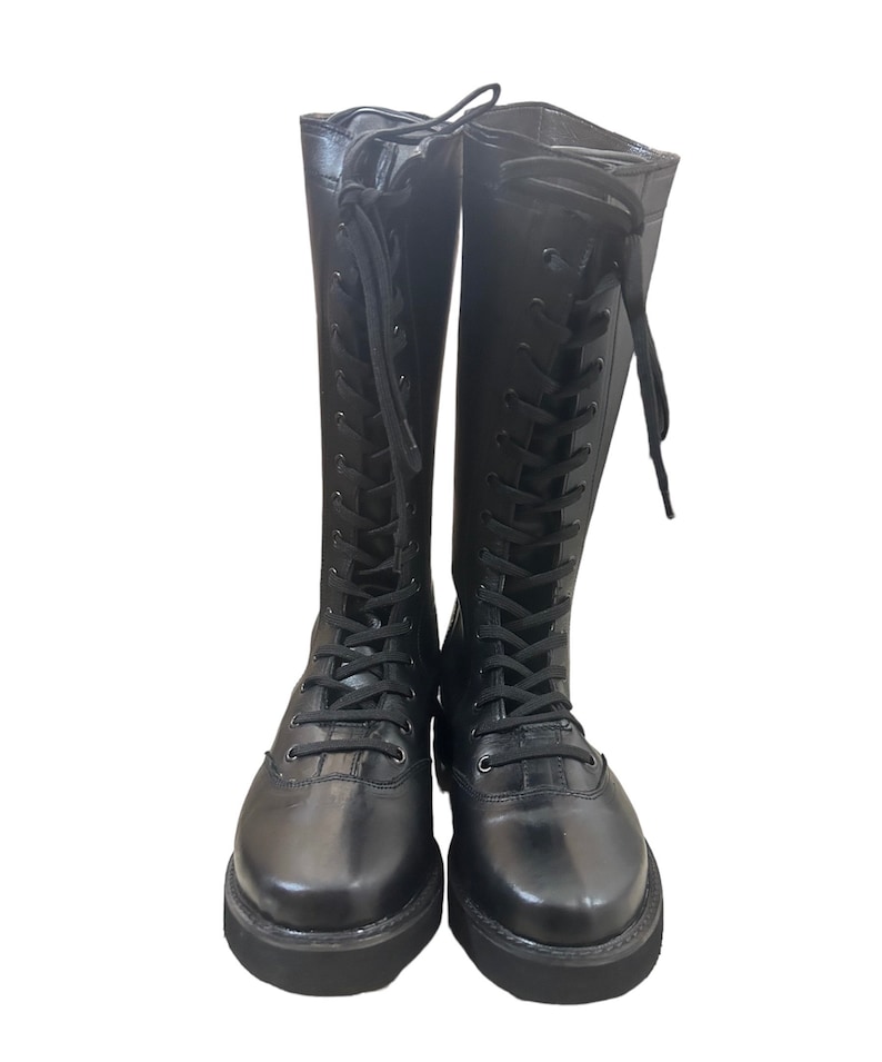 Puede incluir: Botas negras de cuero hasta la rodilla con cordones en la parte delantera y suelas gruesas.