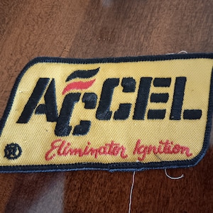 May include: Yellow embroidered patch with black text that reads "ACCEL Eliminator Ignition". The logo features a red and black flame design.