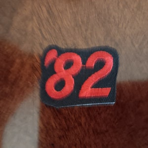 May include: A black and red embroidered patch with the number "82" in red.