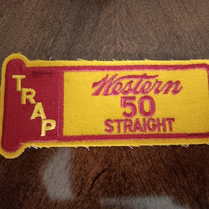 May include: A yellow and red embroidered patch with the text "Western 50 Straight" and "TRAP" on it.