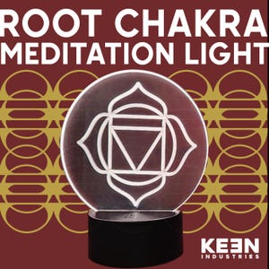 May include: A circular Root Chakra Meditation Light with a white geometric design. The light sits on a black base, with the text "ROOT CHAKRA MEDITATION LIGHT" at the top. The background is a deep red with gold circular patterns.