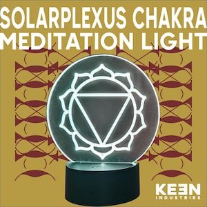 Puede incluir: Una luz de meditación del chakra del plexo solar redonda e iluminada. La luz presenta un diseño geométrico blanco dentro de un círculo, sobre una base negra. Las palabras "SOLAR PLEXUS CHAKRA MEDITATION LIGHT" se muestran en letras blancas.