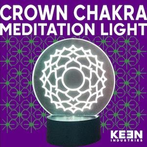 May include: A round, illuminated light with a white floral design, labeled "CROWN CHAKRA MEDITATION LIGHT." The light sits on a black base against a purple background with a green star pattern. The Keen Industries logo is in the bottom right.