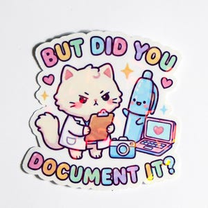 以下が含まれることがあります： 「BUT DID YOU DOCUMENT IT？」のテキストが入った、漫画の猫が実験用白衣を着てクリップボードを持っているカラフルなステッカー。ペン、カメラ、ハートの付いたノートパソコンも含まれています。