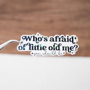 May include: A white sticker with black text that reads "Who's afraid of little old me? You should be." The sticker has a glittery finish.