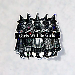 May include: A sticker featuring five witches in black hats and dresses, standing together. The illustration is in black and white with colorful accents. The text "Girls Will Be Girls" is displayed on a banner across the image.