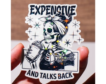 May include: A white sticker with a black and white illustration of a skeleton with a bandana drinking from a cup. The text "Expensive and Difficult and Talks Back" is printed on the sticker.