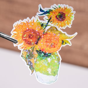 May include: A holographic sticker featuring a painting of three sunflowers in a vase. The sunflowers are yellow with brown centers and green leaves. The vase is clear glass with a green tint.