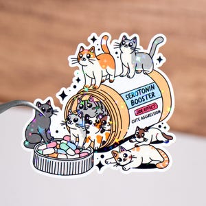 May include: A cartoon illustration of a pill bottle labeled "Serotonin Booster" with a side effect of "Cute Aggression". The bottle is filled with colorful pills and surrounded by adorable cartoon cats.