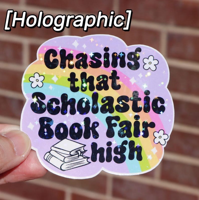 May include: A holographic sticker with a rainbow and stars. The sticker says "Chasing that Scholastic Book Fair high."