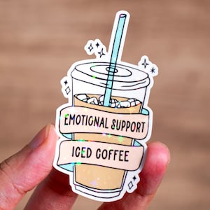 Op de afbeelding: Een sticker met een cartoon afbeelding van een glas ijskoffie met een rietje en de tekst "Emotional Support Iced Coffee".