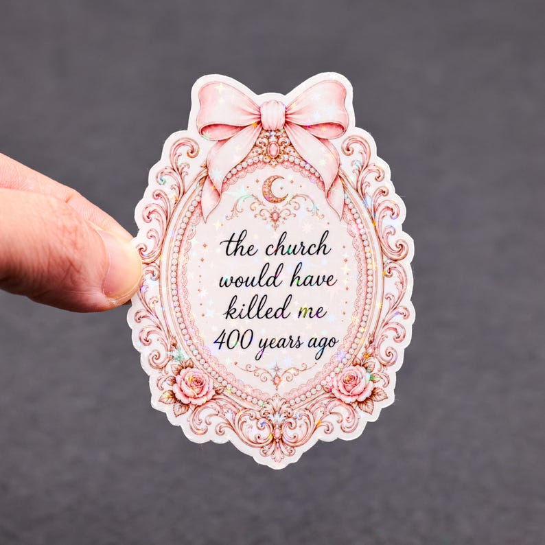 May include: A pink sticker with a decorative oval frame, bow, and roses. The text reads "the church would have killed me 400 years ago." The sticker has a glittery, iridescent finish.