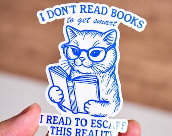 May include: A blue and white sticker with a cat wearing glasses and reading a book. The text on the sticker reads "I don't read books to get smart I read to escape this reality."