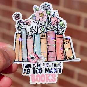 May include: A sticker with a stack of colorful books with flowers growing out of the top. The sticker says "There is no such thing as too many books".