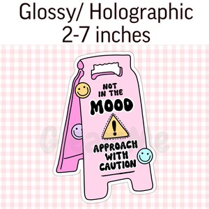 May include: Pink and yellow glossy holographic sticker with a caution sign that says "Not in the mood! Approach with caution".