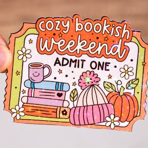 May include: A colourful ticket with the text "Cozy Bookish Weekend" and "Admit One". The ticket features illustrations of a cup of coffee, a stack of books, a pumpkin, and a winter hat.