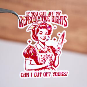 May include: A sticker featuring a vintage-style illustration of a woman holding a knife, with the text "IF YOU CUT OFF MY REPRODUCTIVE RIGHTS CAN I CUT OFF YOURS?" in red and white. The woman is wearing a red dress and a headscarf.