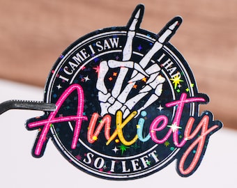 May include: A black and white sticker with a skeleton hand making the 'I came, I saw, I had anxiety, so I left' gesture. The sticker has a glittery finish and the text is in a rainbow font.