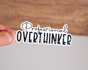 May include: A white sticker with black text that reads "Professional Overthinker" with iridescent glitter accents.
