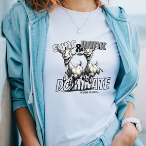 May include: White t-shirt with a graphic of two cartoon goats running and the text "Sync & Wink Dominate The Game of Goats..."