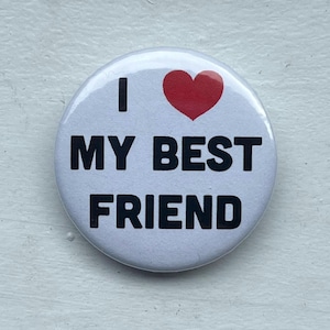 Peut inclure: Un badge rond blanc avec le texte noir I, un symbole de cœur rouge et le texte noir MY BEST FRIEND centré sur la surface. Le motif est imprimé dans une police sans empattement en gras avec une finition brillante sur la face du badge.