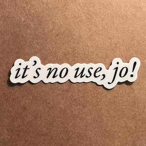 May include: A white die-cut sticker featuring the text "it's no use, jo!" in a black cursive typeface. The sticker has a smooth, rounded border that follows the contour of the lettering, providing a clear and distinct visual presentation for the user.