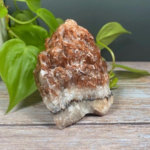May include: A large, rough, brown and white calcite crystal with a layered, striated texture. The crystal has a natural, organic shape and is a popular choice for crystal healing and meditation.