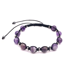 May include: A purple amethyst gemstone bracelet with black cord and silver beads.