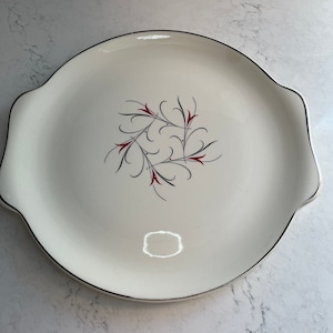 May include: White serving platter with a black and red floral design. The platter has two handles on the sides.