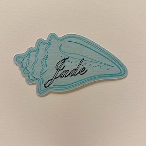 May include: A set of three ceramic mugs with a speckled, matte finish. The mugs are in shades of cream, light gray, and dark gray. Each mug has a simple, minimalist design, perfect for coffee or tea.