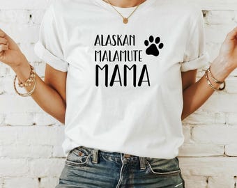 Pode incluir: Camiseta branca com texto preto que diz "Alaskan Malamute Mama" com um gráfico de pegada.