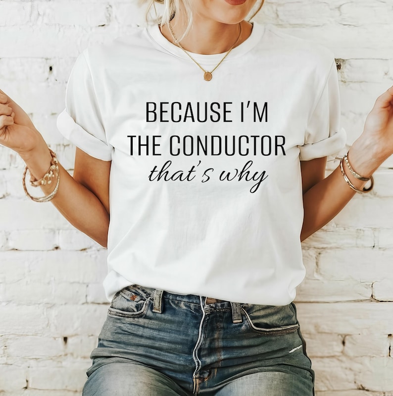 May include: White t-shirt with the text "Because I'm the conductor that's why" printed on it.